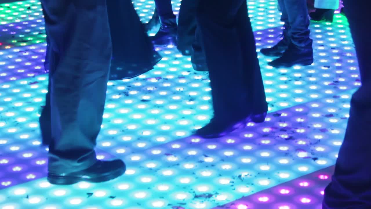 people dancing on a led dance floor with different bright colors during a party at night