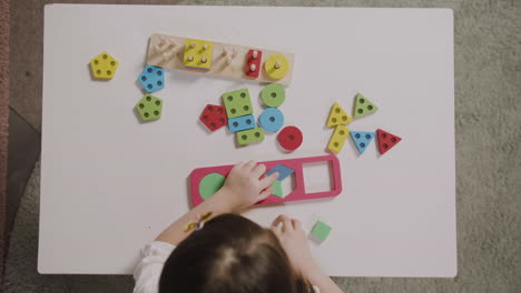 vista dall'alto della bambina che gioca con il selezionatore di forme in una scuola montessori