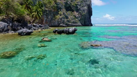 Cinematic-flight-over-turquoise-Caribbean-Sea-water-with-rocks-along-tropical-coastline-of-playa-fronton,samana