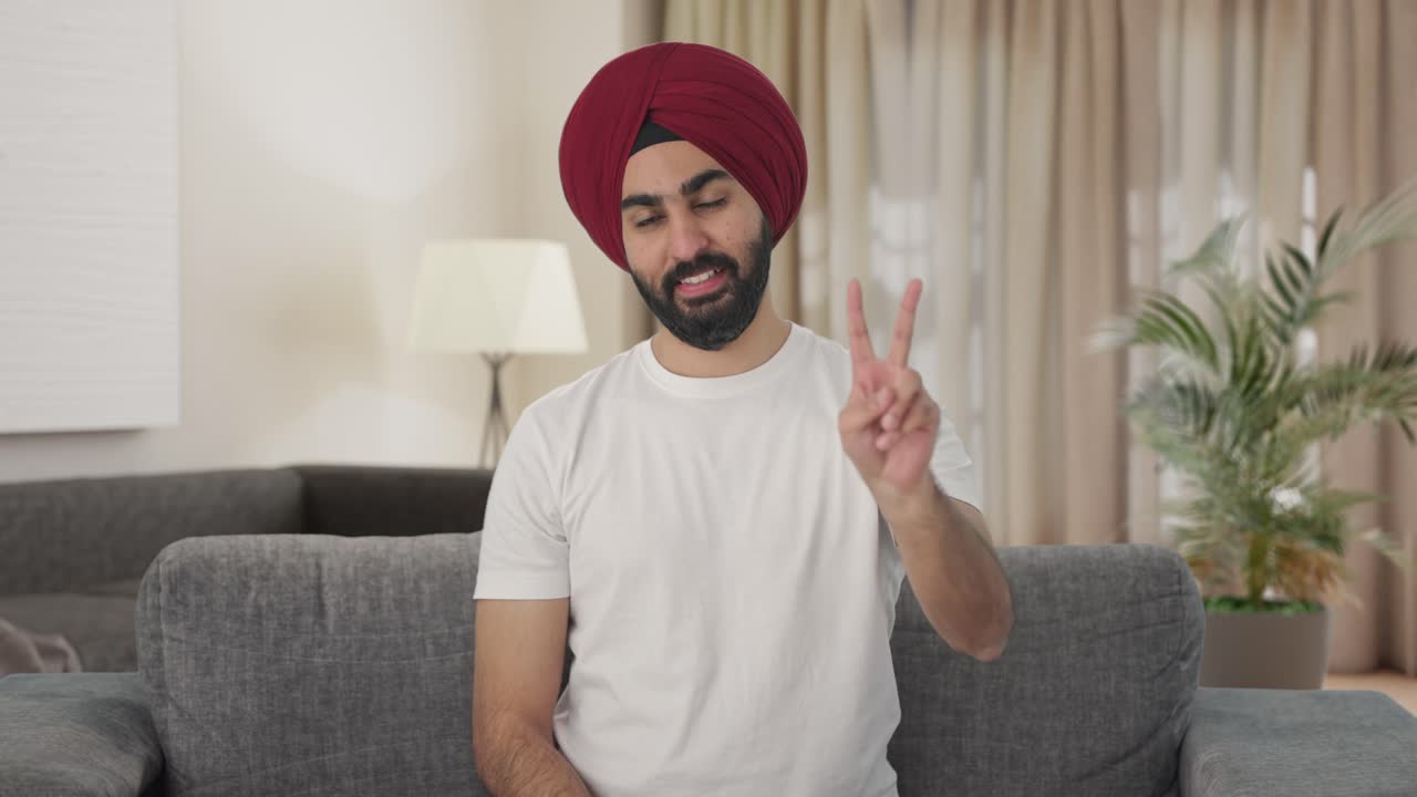 Uomo indiano Sikh felice che mostra il segno della vittoria