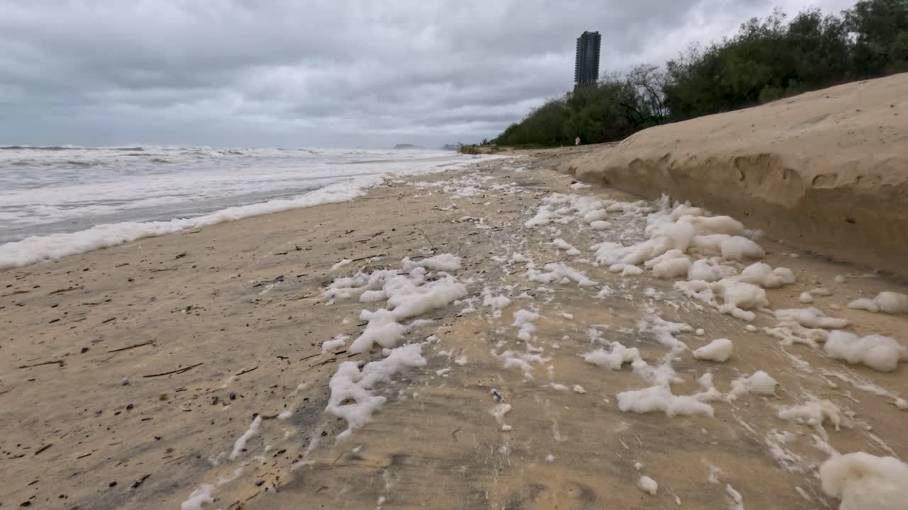 бурная пляжная сцена с пеной и эрозией, демонстрирующая турбулентную погоду и воздействие на окружающую среду