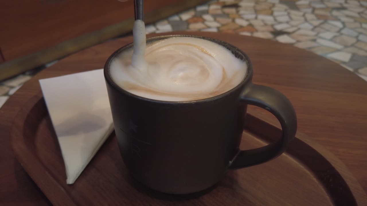 Stirring Cappuccino with a teaspoon in a bar