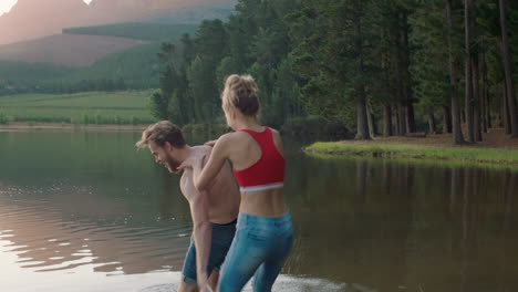 happy couple splashing in lake at sunset young man picks up girlfriend splash in water having fun game enjoying romantic summer love