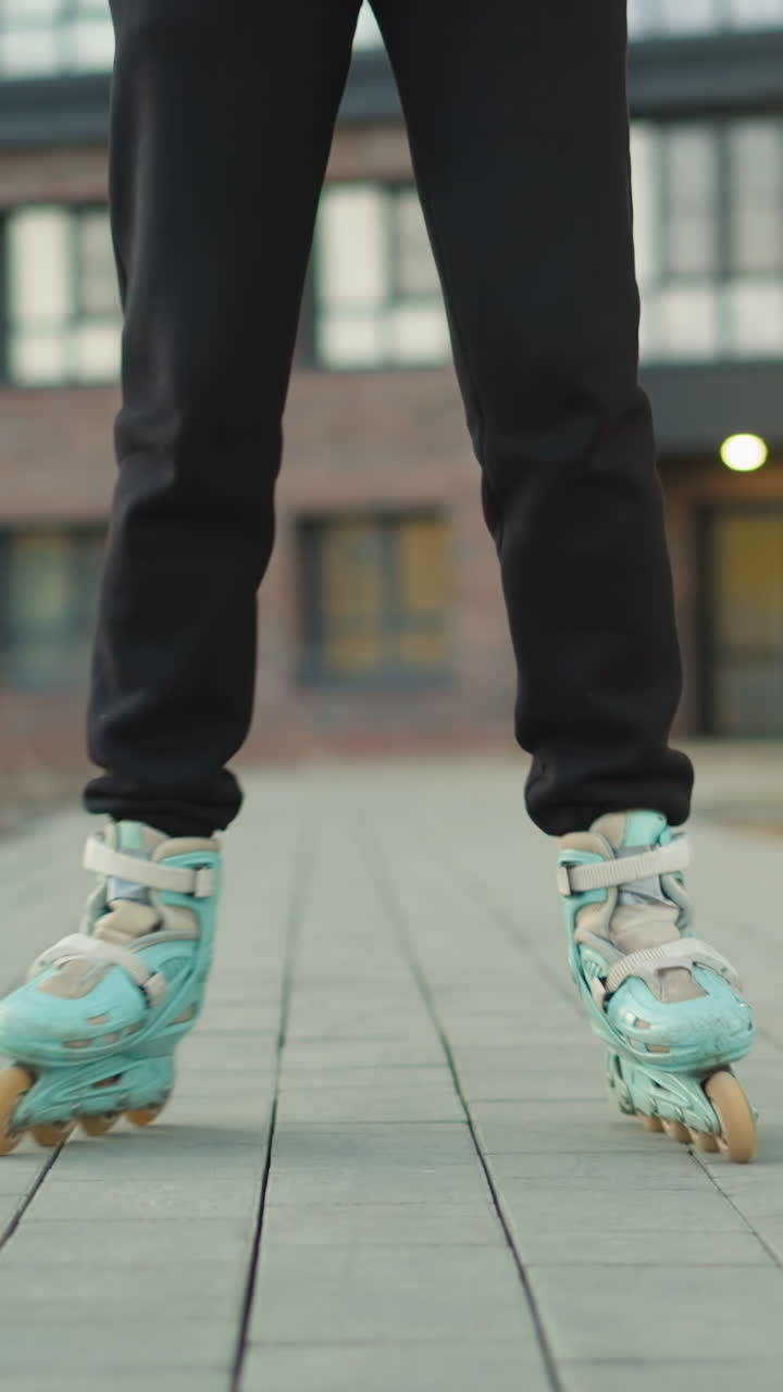 Front shot the motion of rollerblades as they glide smoothly over a paved path in a park. Residential buildings are visible in the background, showcasing the urban environment and outdoor activity