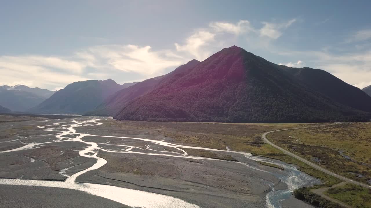 Awesome Drone Flight over the stony riverbed of Waimakariri River, Canterbury, New Zealand. It's a sunny summer day. In the background, you can see Arthurs Pass National Park.