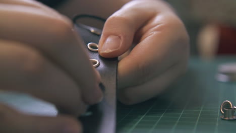 professional designer fixes eyelets in black leather belt