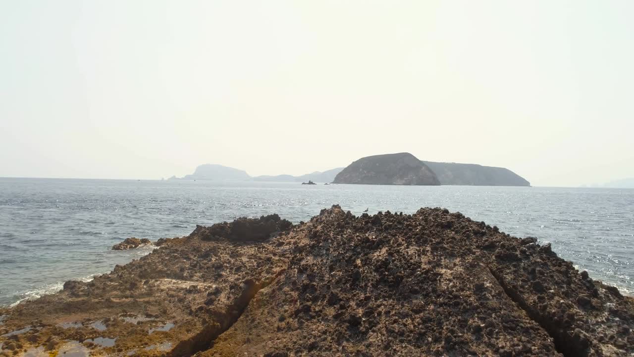 vista aérea de un pequeño atolón con rocas y arena. barco blanco y rojo desde un dron.
