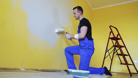 attractive worker doing renovation wall. professional painter with brush and roller decorating indoor of house.