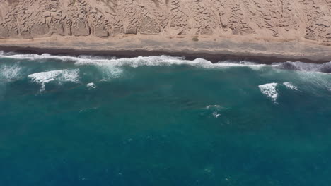 Panoramic-aerial-tilt-reveal-shot-of-Vlychada-in-Santorini,-Greece-,-4K-prores