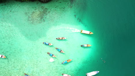 varios barcos tradicionales asiáticos navegando por las aguas poco profundas de arrecife de coral turquesa, asia sureste