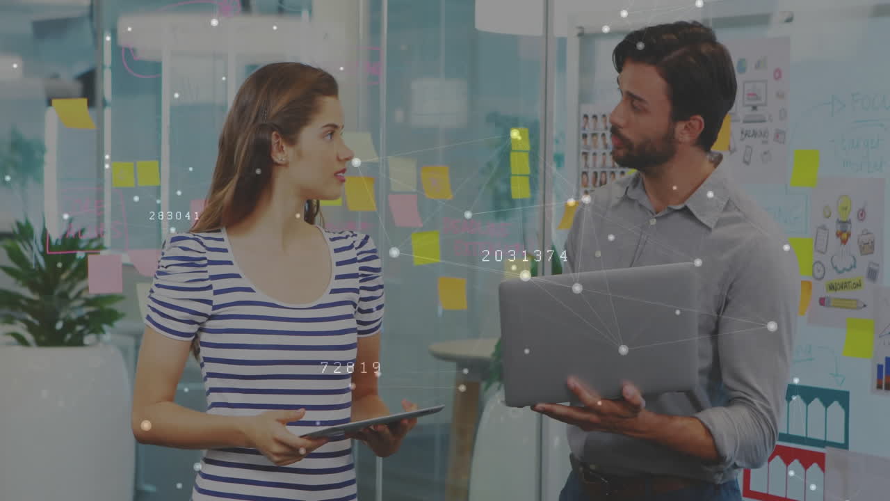Man and woman discussing business strategy in office with sticky notes and floating network overlay