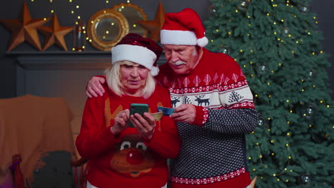 Großmutter-Einer-älteren-Familie,-Die-Mit-Kreditkarte-Und-Smartphone-Weihnachtsgeschenke-Einkauft