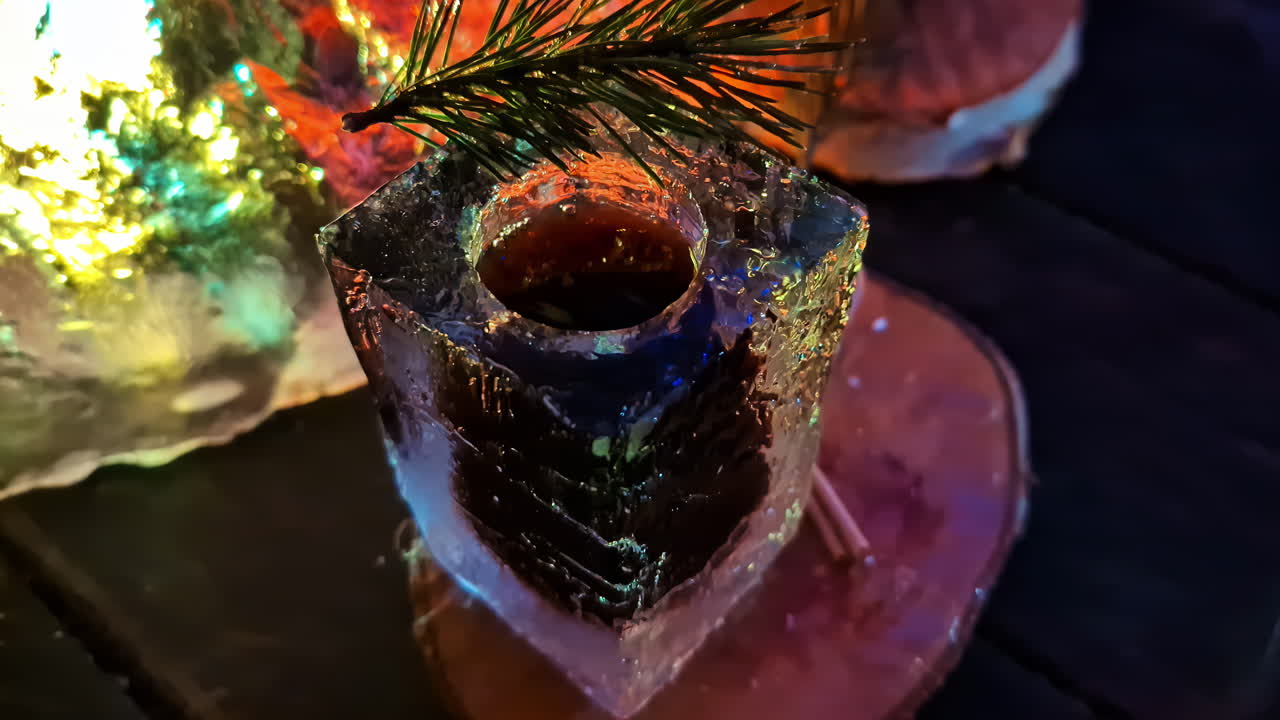 Bevanda calda fumante servita in una tazza di ghiaccio intagliato con luci festive di notte.