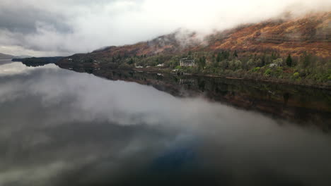 Vista-Frontal-Por-Drones-Del-Majestuoso-Lago-Rodeado-De-Imponentes-Montañas-En-Un-Día-Nublado