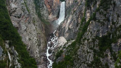 Aerial-landing-shot-of-splashing-waterfall-with-rocky-stream-in-mountains-of-triglav-Nationalpark,-Slovenia