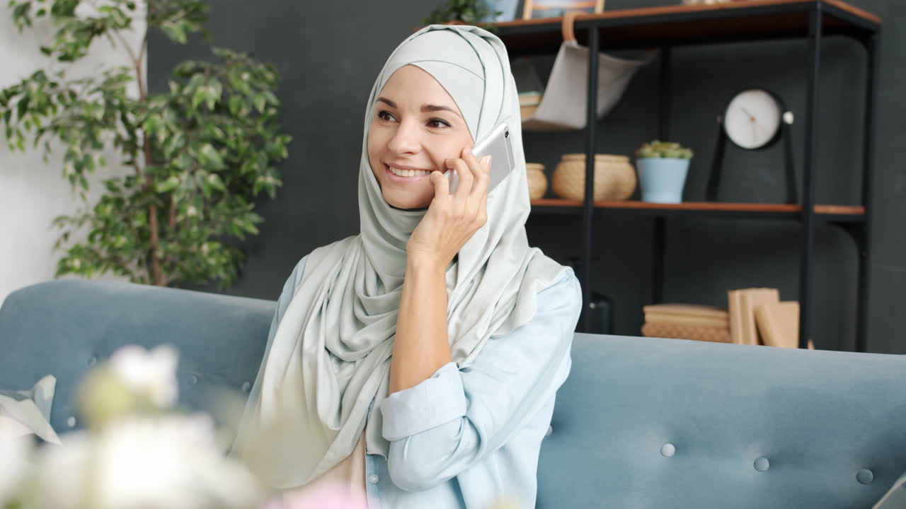 Woman wearing hijab talking on phone at home