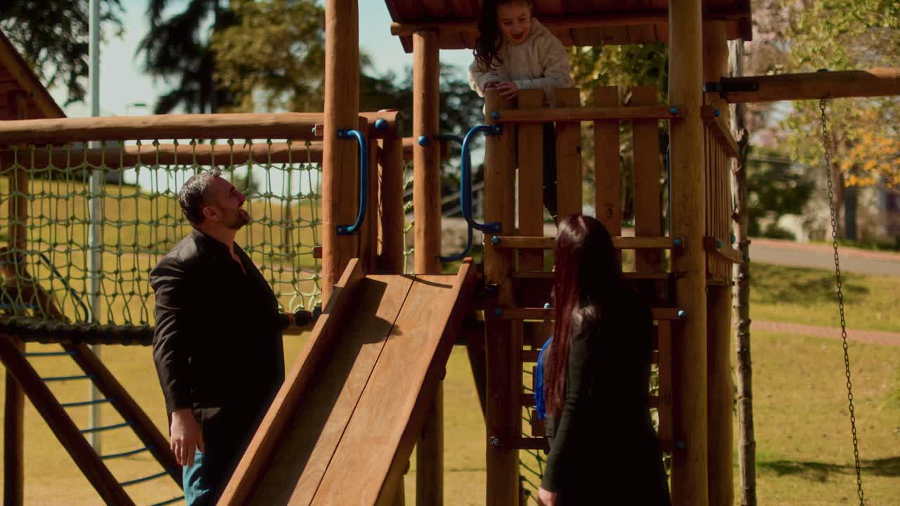 Family playing together at a wooden playground in a park