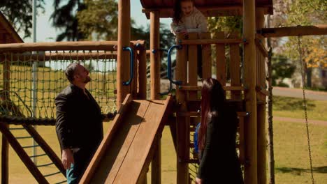Family playing together at a wooden playground in a park