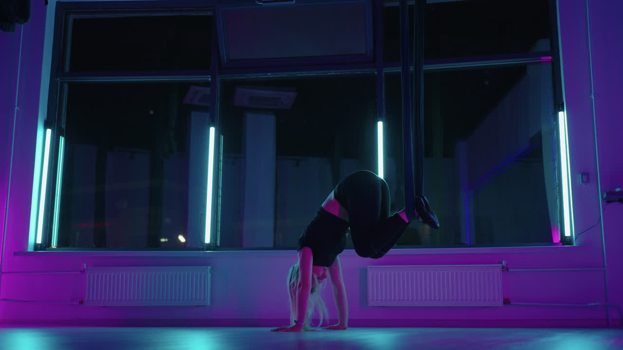 una donna sta facendo esercizio fisico usando un'amaca per lo yoga antigravità nella sala fitness
