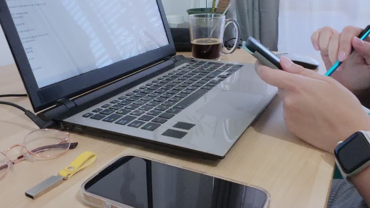 Person reading or reviewing documents on a tablet, with laptop and coffee on the desk.
