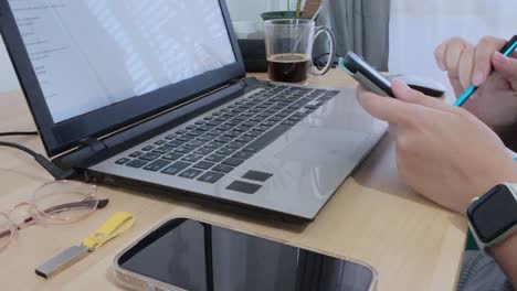 person reading or reviewing documents on a tablet, with laptop and coffee on the desk.