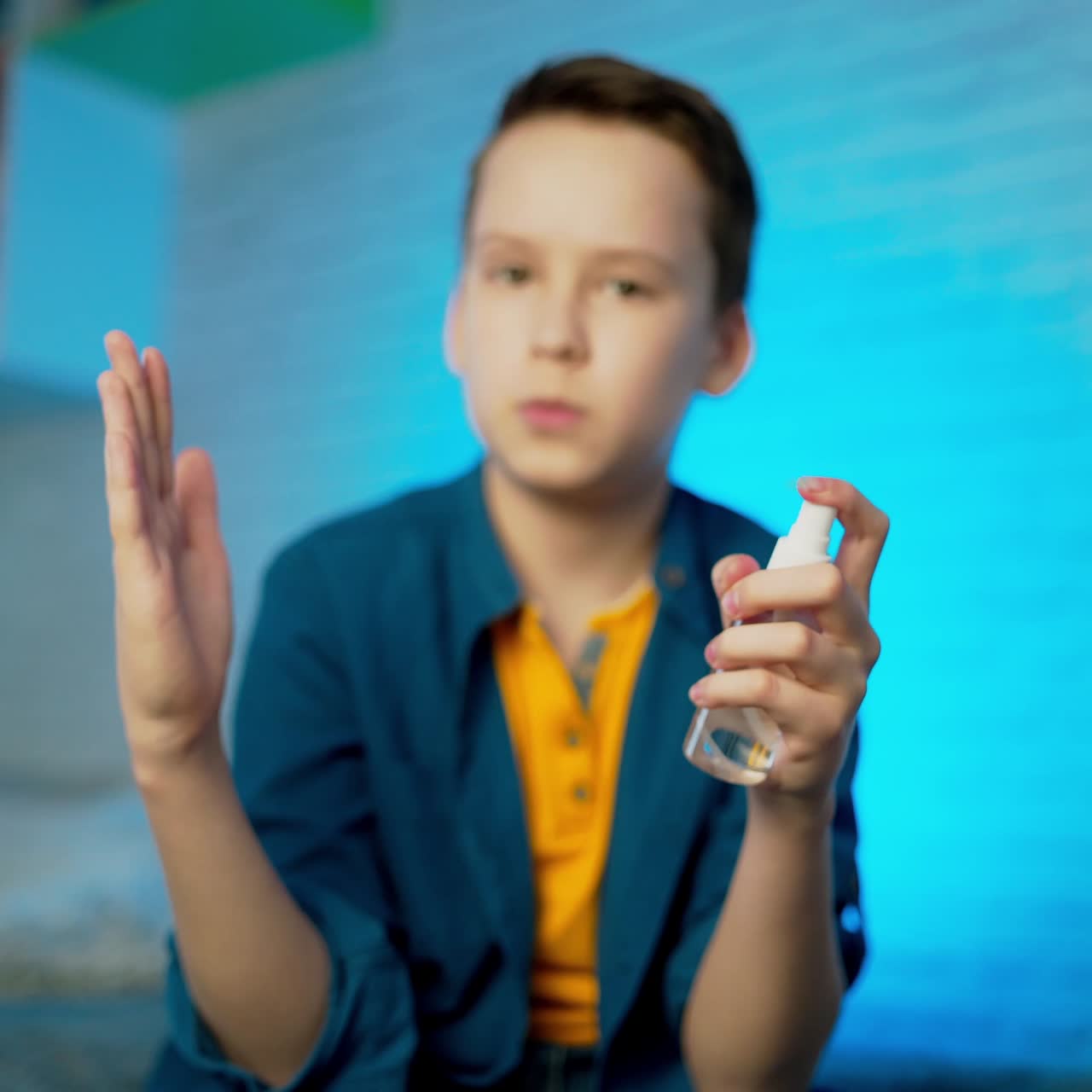Boy applying alcohol spray or anti bacteria spray to prevent spread of germs, bacteria and virus. Personal hygiene concept.