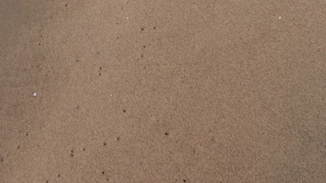 yellow sandy beach with sea wave water rushing towards it at morning