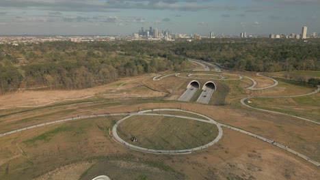 Houston-Texas-Skyline-over-Memorial-Park-Land-Bridge-aerial-backwards-tracking-pan-up-reveal-on-a-sunny-day