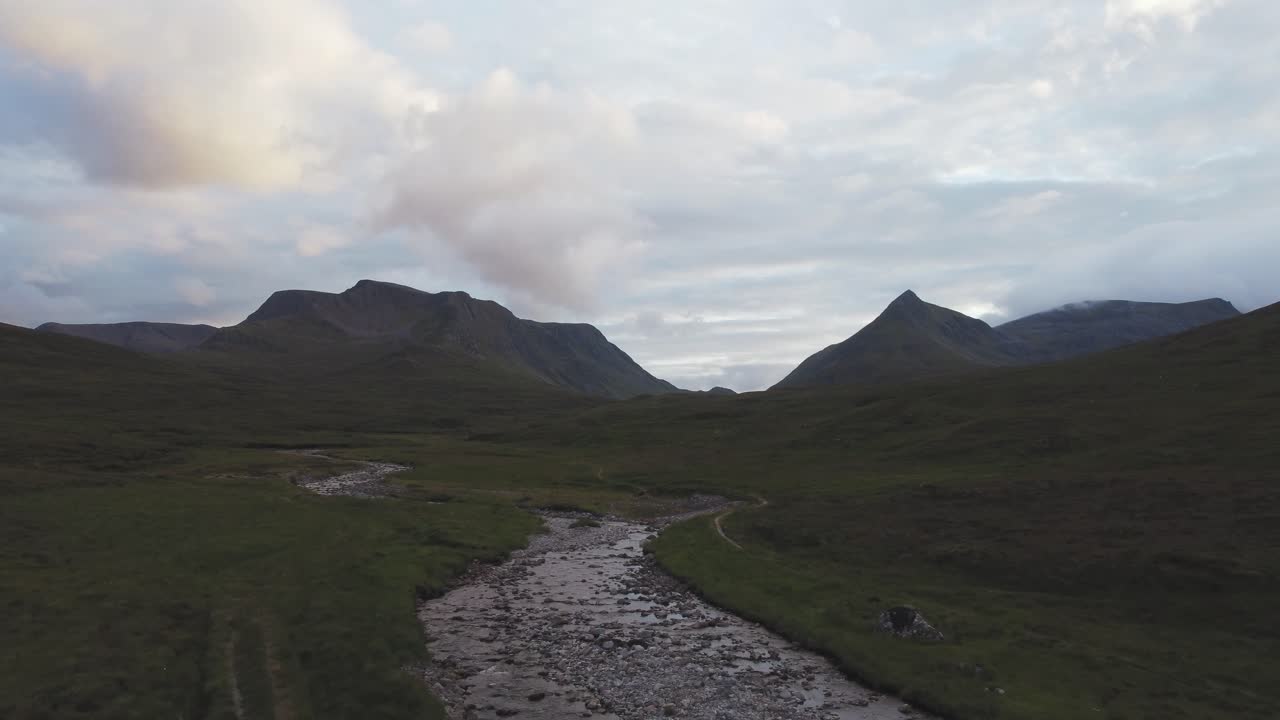 Drone footage from the Scottish highlands flying between mountains and over a stream