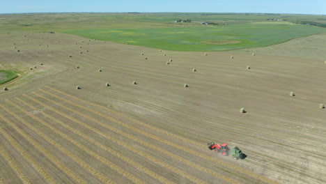 super wide angle aerial of tractor harvesting hay bales near saskatchewan