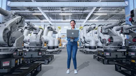 ingeniera con una computadora portátil en una fábrica con robots