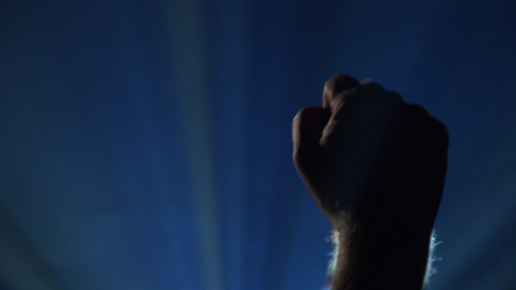 Pugno che batte a ritmo durante un concerto attraverso fasci di luce