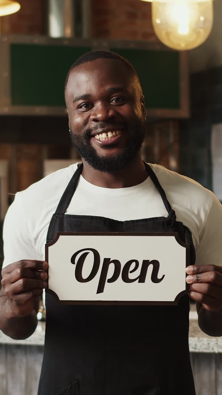 Smiling employee holding open sign