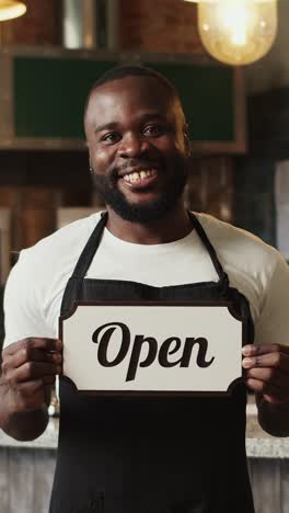 smiling employee holding open sign