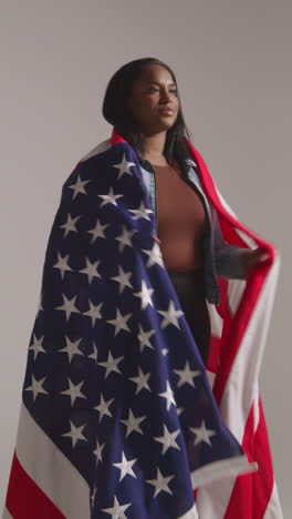 vertical video studio shot of woman wrapped in american flag celebrating 4th july independence day 2