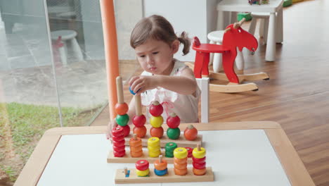 Niña-De-3-Años-Jugando-Con-Un-Anillo-De-Apilamiento-Sensorial-De-Madera-Para-El-Aprendizaje-Básico-De-Conteo-En-La-Sala-De-Juegos-Para-Niños---Cámara-Lenta