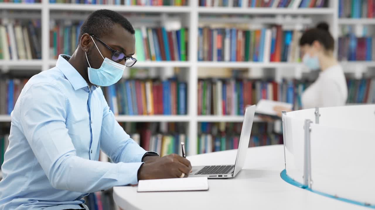 Student working in a library during COVID-19 pandemic