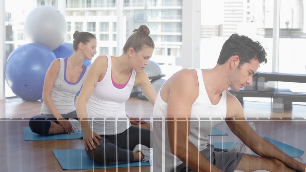 Foreground man performing seated side stretch on blue mats after instructor cue, improving fitness