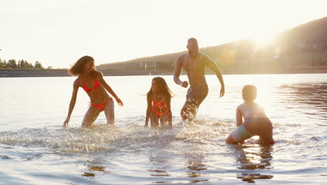 Padres-Con-Niños-Jugando-Y-Chapoteando-En-El-Lago