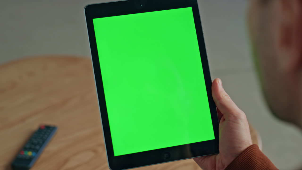 Man holding green screen tablet at house closeup. Unknown freelancer working