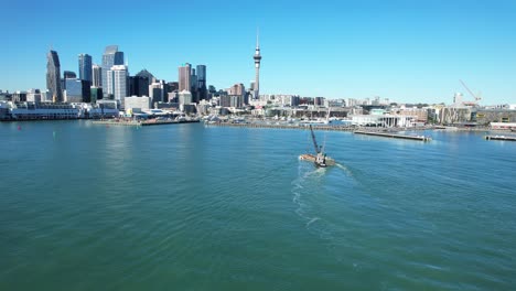 auckland cityscape and harbor with a boat and crane on a clear day