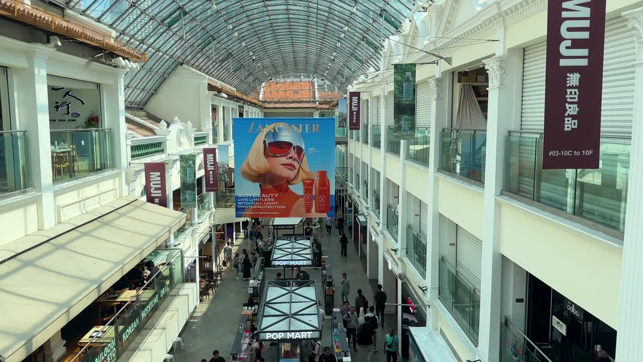Camera tilts from bustling shopping area to arched glass ceiling, bright daylight, modern architecture