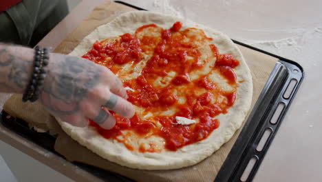 adding ripped mozzarella to pizza