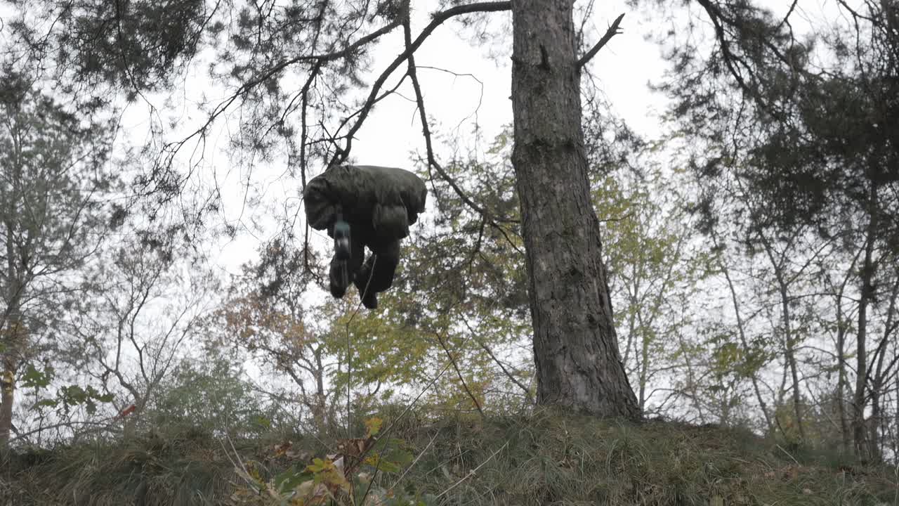 paintballer masculino haciendo salto en picada en el bosque