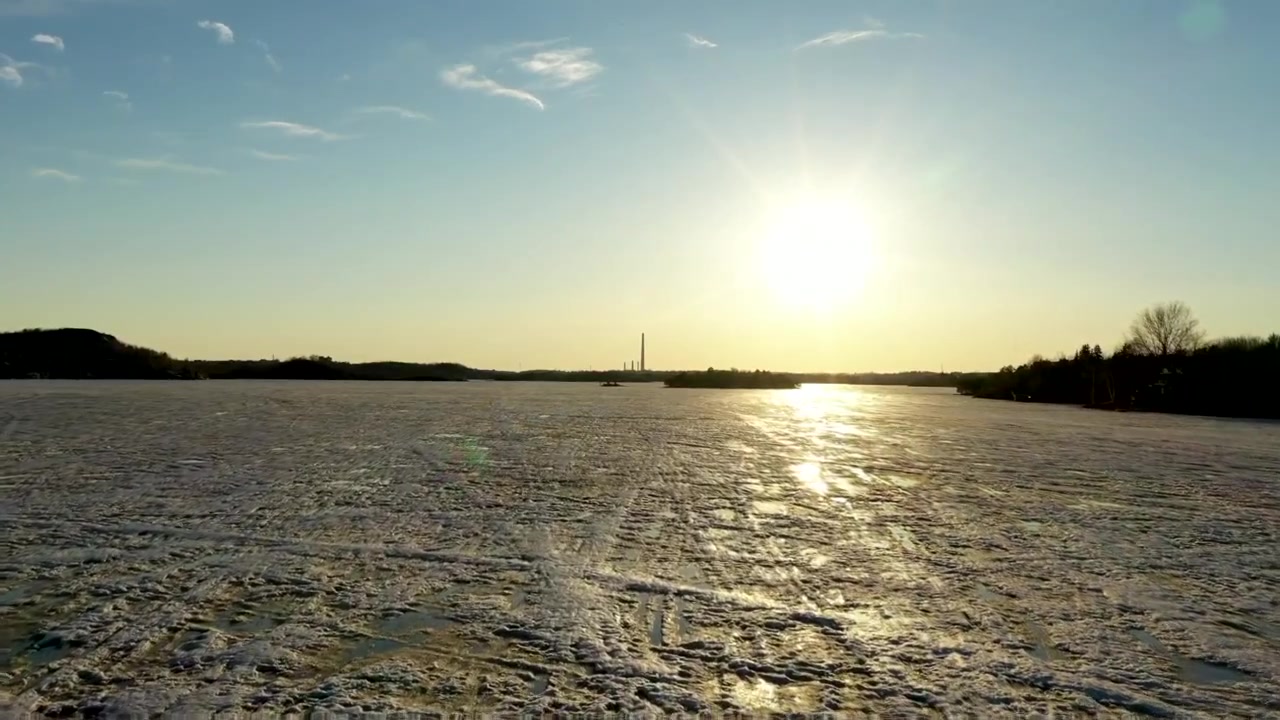 Droneoptagelse over frossen måneskinsstrand i Sudbury, Ontario under solnedgang, med en smuk refleksion på isen