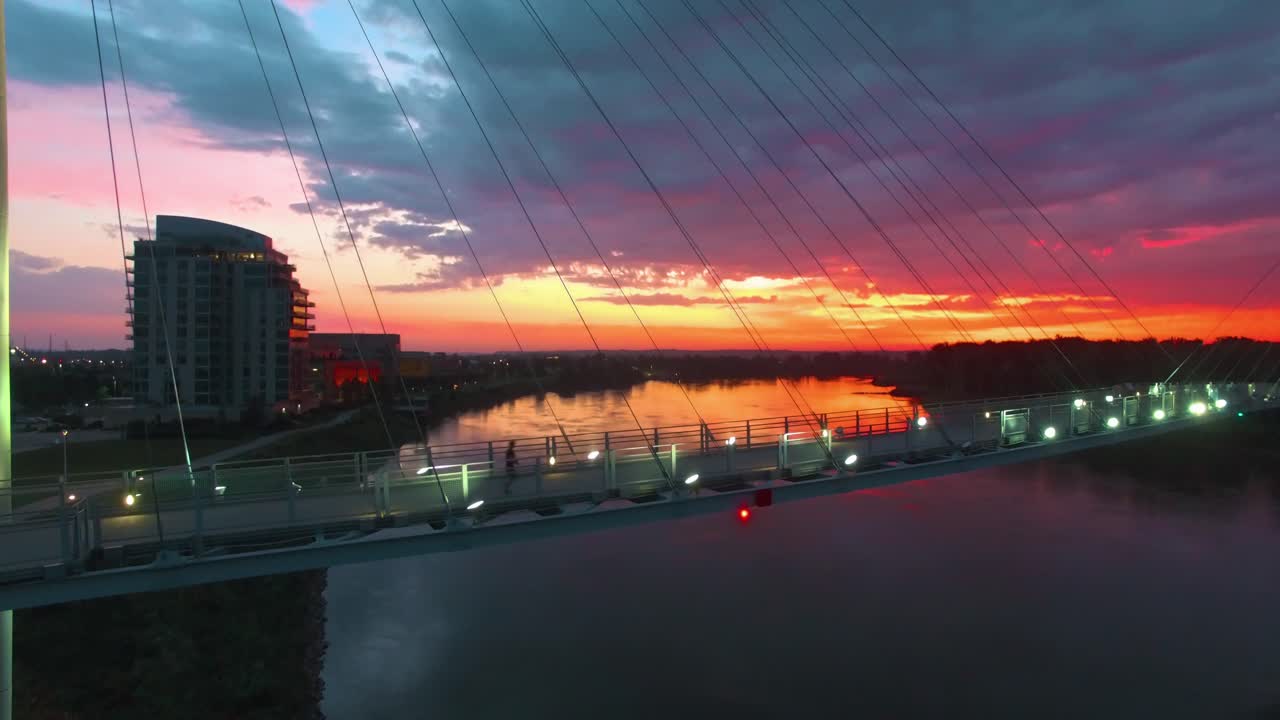 Runner crossing bridge over river during colorful midwest sunrise