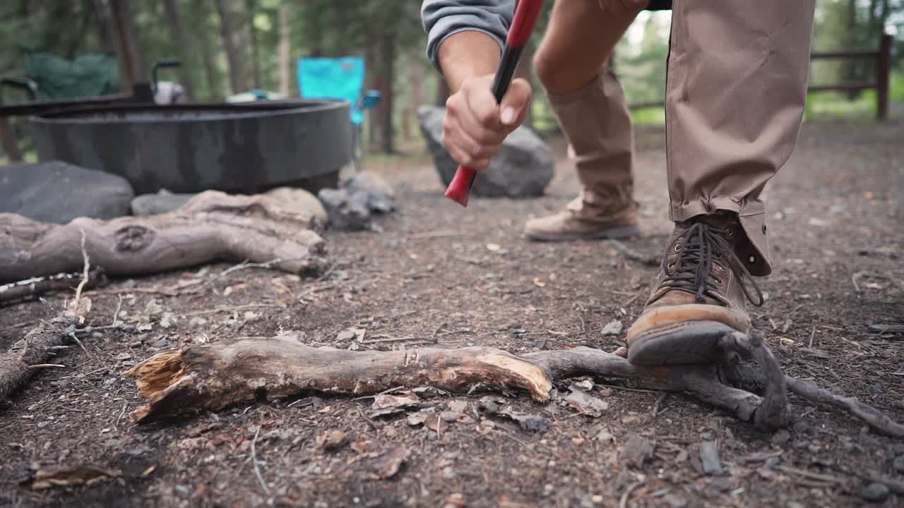 chopping a wood branch with an axe around a campsite epic flying wood chips slow motion
