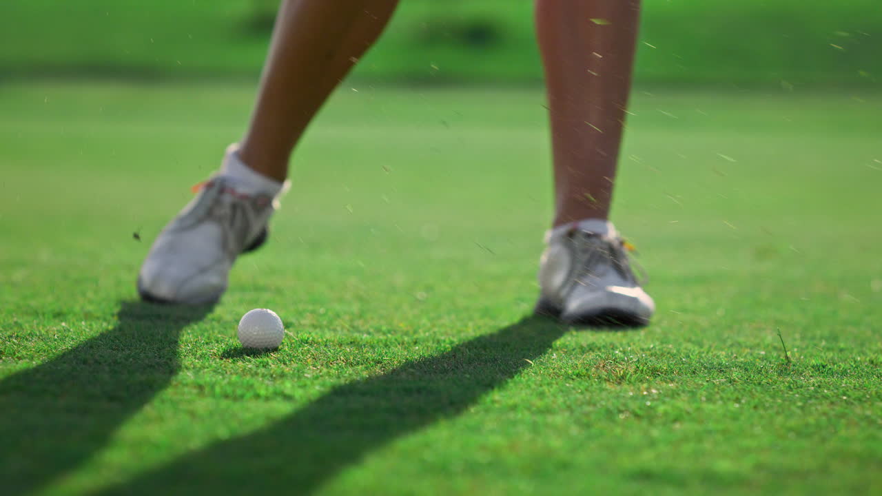las piernas de la mujer juegan al golf en el campo de césped.