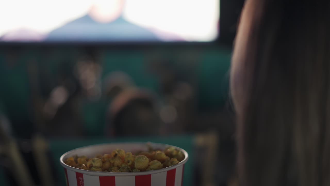 filmato sopra la spalla - donna mangia popcorn al cinema