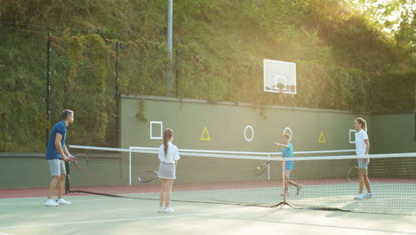 familia feliz jugando tenis en una cancha al aire libre en verano 1
